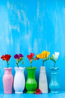 Fünf vasen mit freesien auf blauem grund. schöne blumen.