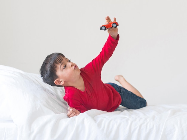 Full Shot Boy mit Spielzeug im Bett