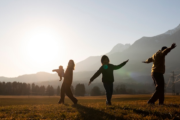 Full-Shot-Familiensilhouette in der Natur bei Sonnenuntergang