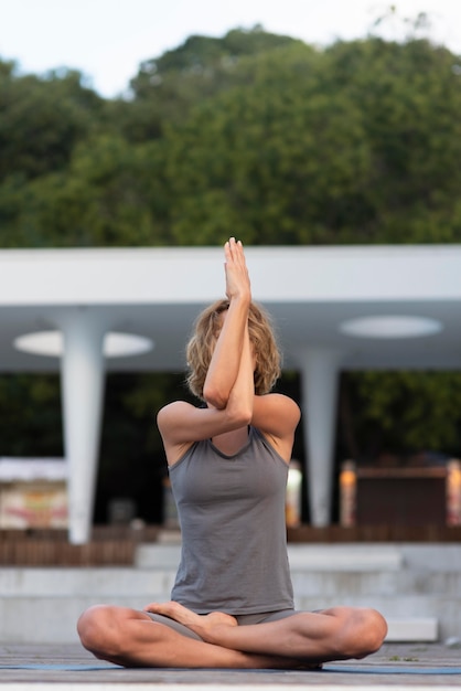 Full Shot Frau macht Sukhasana Pose draußen