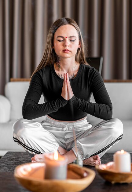 Full Shot Frau meditiert mit Kerzen