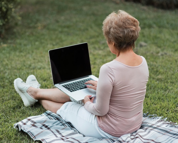 Full Shot Frau sitzt auf Laptop