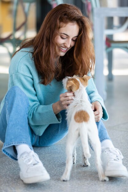 Full Shot Frau spielt mit niedlichen Hund