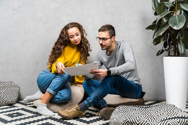 Full shot freunde sitzen auf dem boden und studieren