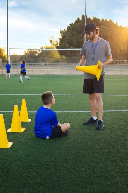 Kostenloses Foto full-shot-fußballtrainer, der kinder unterrichtet