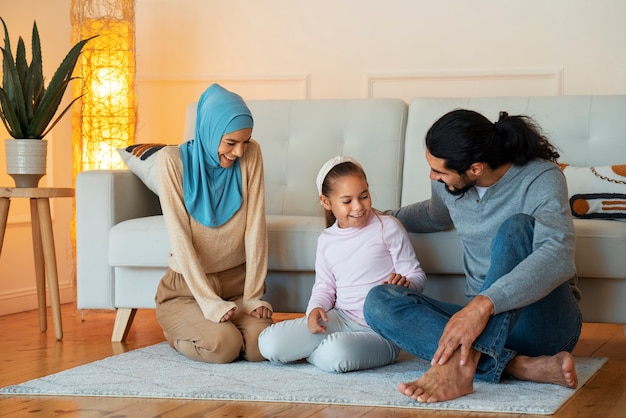 Kostenloses Foto full shot glückliche islamische familie, die auf dem boden sitzt