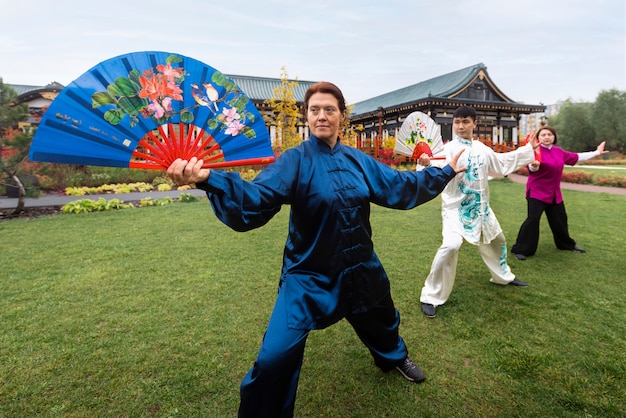 Kostenloses Foto full-shot-gruppe, die tai chi im freien praktiziert