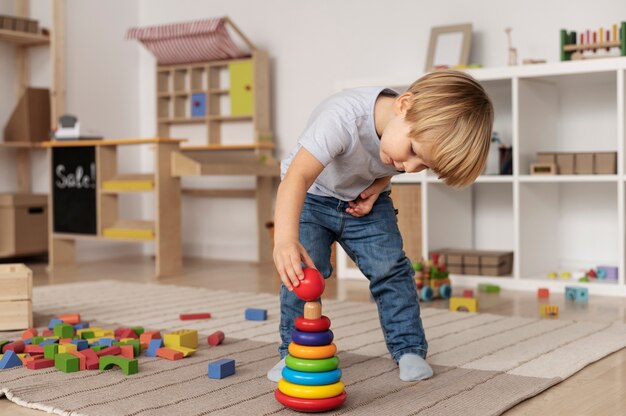 Full-Shot-Kind, das auf dem Boden mit Holzspielzeug spielt