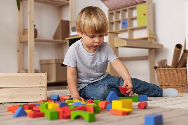 Full-Shot-Kind, das mit bunten Spielsachen auf dem Boden spielt