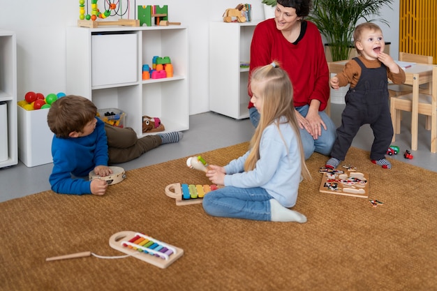 Kostenloses Foto full-shot-lehrer, der kindern beim lernen zuschaut