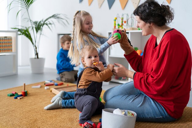 Full-Shot-Lehrer, der kleinen Kindern beim Lernen zuschaut