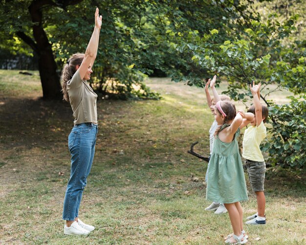 Full Shot Lehrer und Kinder mit erhobenen Händen