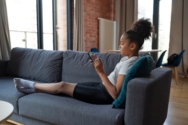 Full Shot Mädchen auf der Couch mit Smartphone