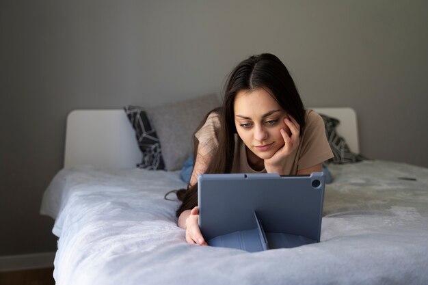 Full-Shot-Mädchen im Bett mit Tablet