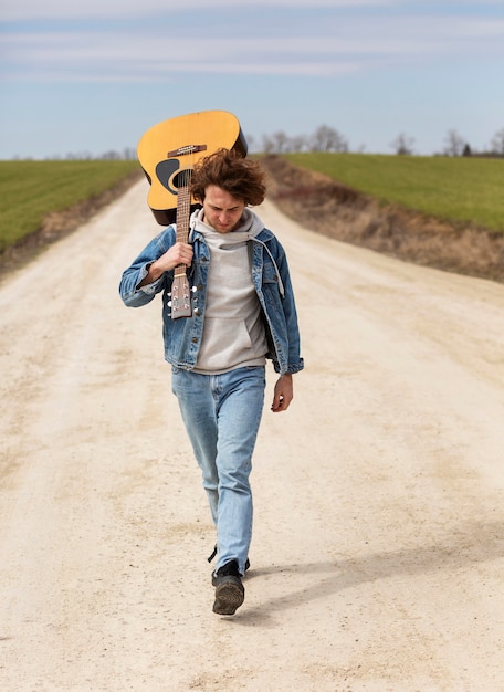 Full Shot Mann geht mit Gitarre