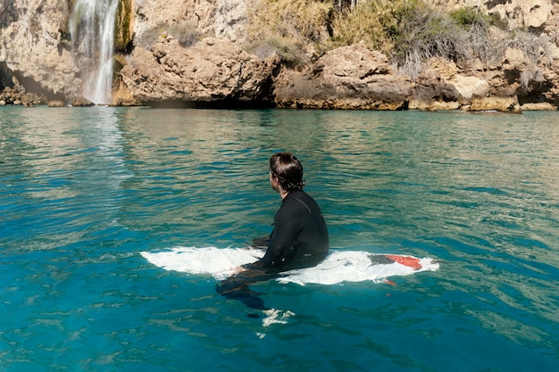 Kostenloses Foto full shot mann sitzt auf surfbrett