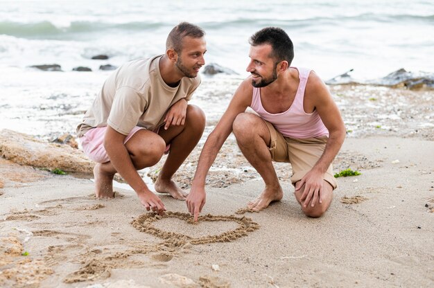 Full Shot Partner ziehen Herz auf Sand