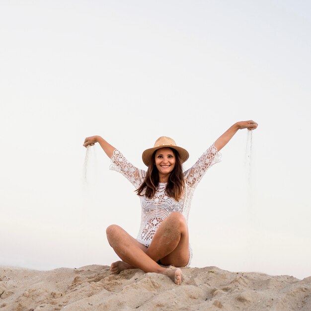 Full Shot Smiley Frau sitzt auf Sand