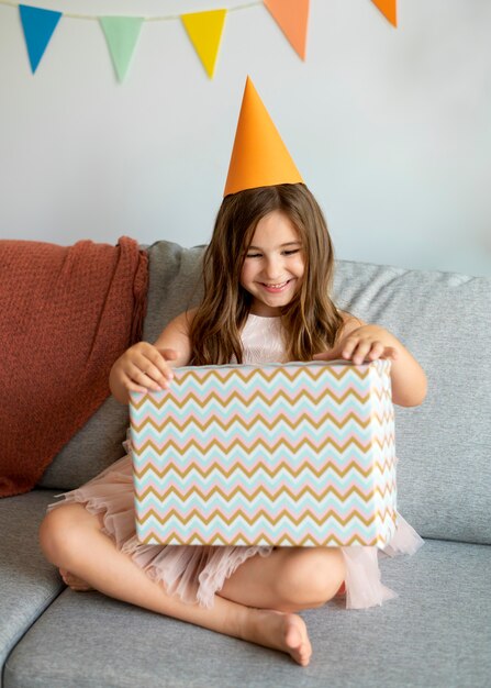 Full Shot Smiley Girl öffnet Geschenk auf der Couch