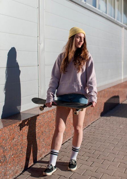 Full Shot Teen Girl hält Skateboard