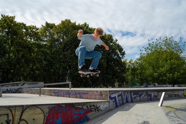 Kostenloses Foto full shot teen macht trick auf skateboard