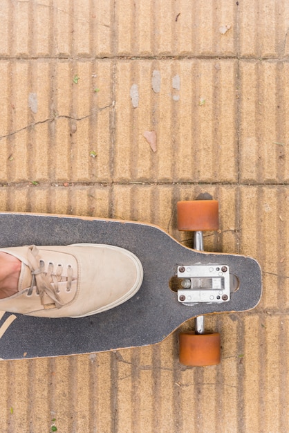 Fuß in Turnschuhen auf Longboard stehen