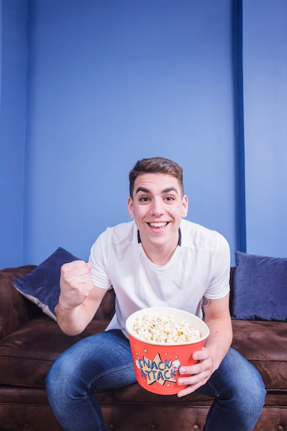 Kostenloses Foto fußballfan auf couch mit popcorn