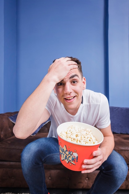 Fußballfan auf Couch mit Popcorn