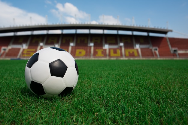 Fußballkugel auf Gras mit Stadionhintergrund