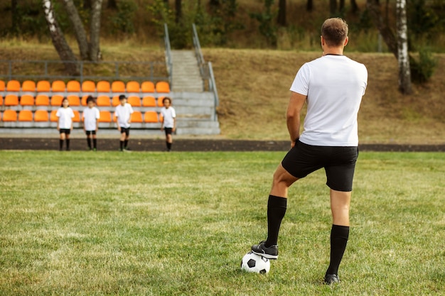 Kostenloses Foto fußballspielende kinder unter aufsicht eines fußballtrainers