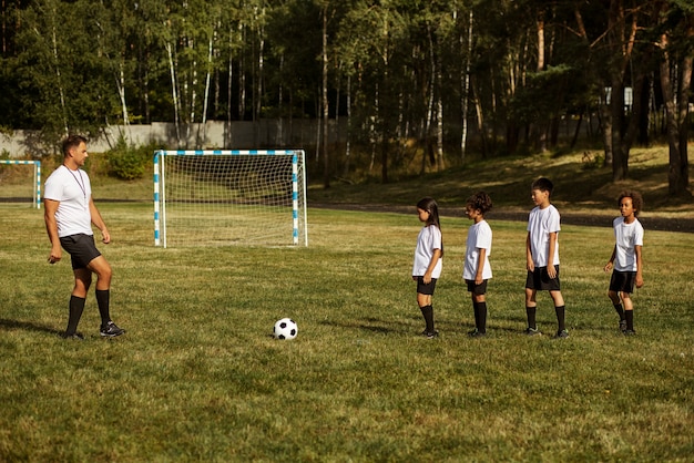 Kostenloses Foto fußballspielende kinder unter aufsicht eines fußballtrainers