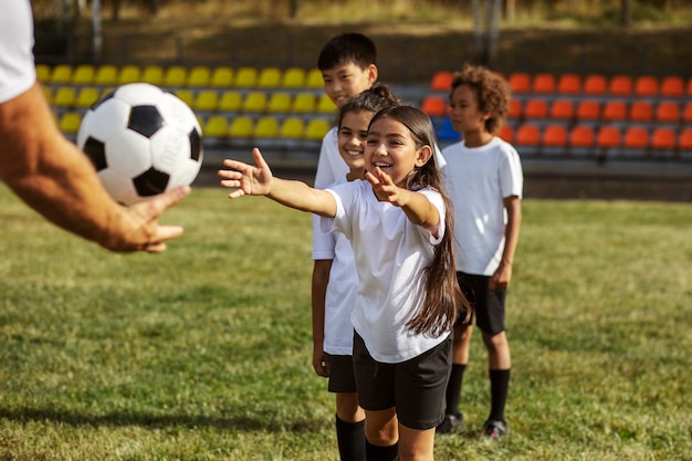 Fußballspielende Kinder unter Aufsicht eines Fußballtrainers
