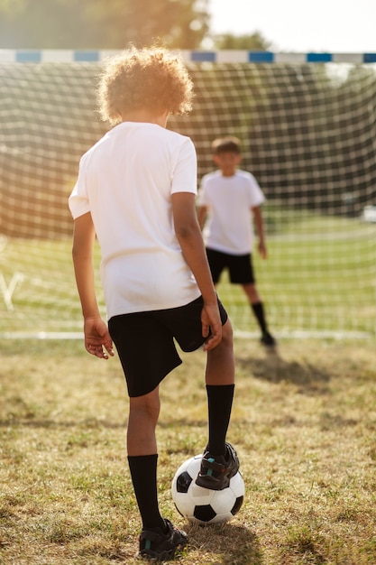 Fußballspielende Kinder unter Aufsicht eines Fußballtrainers