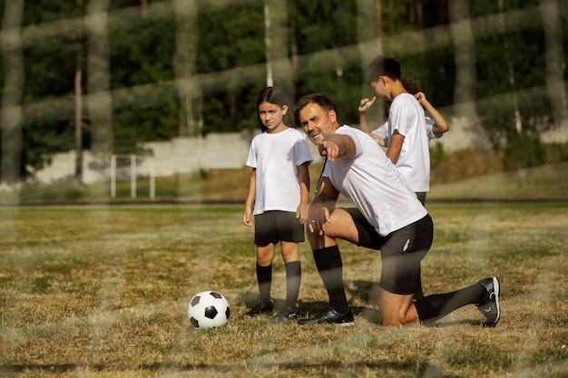 Fußballspielende Kinder unter Aufsicht eines Fußballtrainers