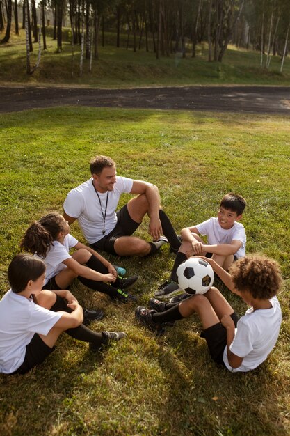 Fußballspielende Kinder unter Aufsicht eines Fußballtrainers