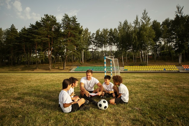 Fußballspielende Kinder unter Aufsicht eines Fußballtrainers