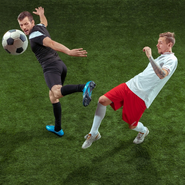 Fußballspieler, der für Ball über grünem Gras angreift