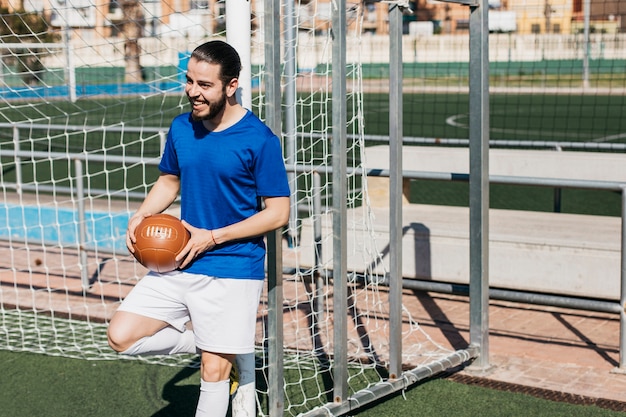 Kostenloses Foto fußballspieler, der gegen pfosten sich lehnt