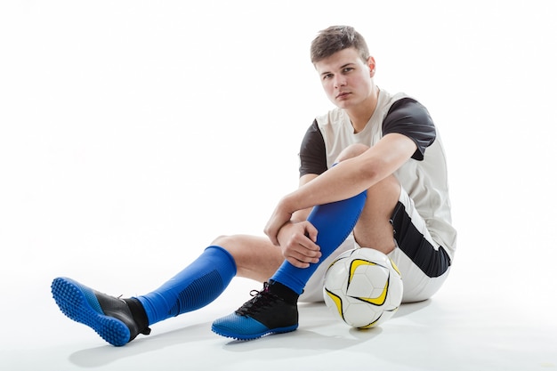 Fußballspieler mit Kugel auf dem Boden sitzen