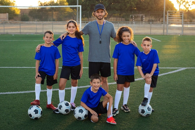 Kostenloses Foto fußballtrainer und kinder, die vorderansicht posieren