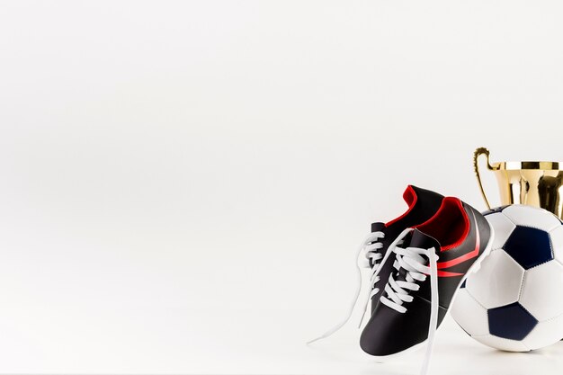 Fußballzusammensetzung mit Schuhen und Ball nahe bei copyspace