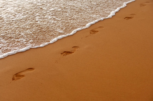 Fußspuren am goldenen sand fußspuren tropischer strand mit meersand im sommerurlaub