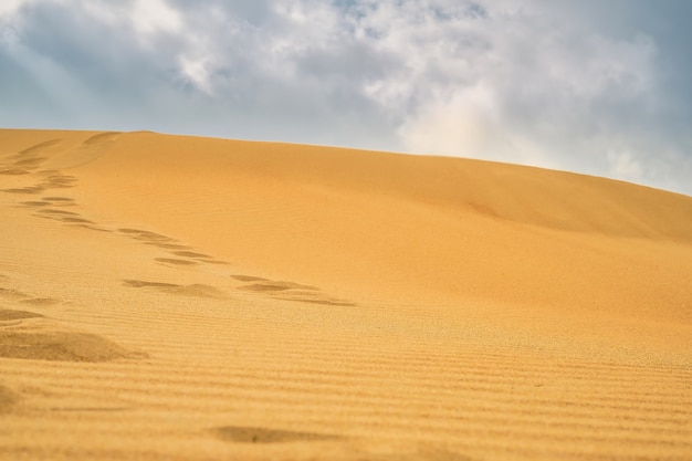 Fußspuren im Sand auf einer Sanddüne an der Schwarzmeerküste. Selektiver Fokus im Mittelgrund auf dem Sand. Dünen gegen den Himmel, Sommerideenbanner