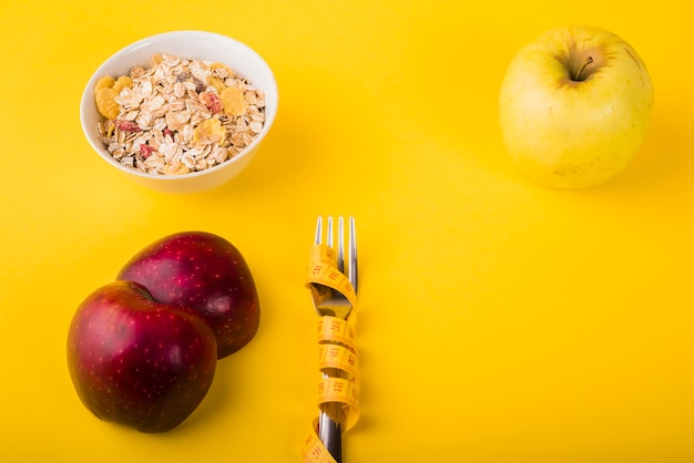 Gabel in Maßband zwischen Obst und Schüssel Müsli