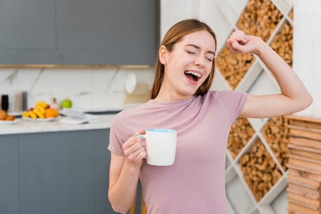 Gähnende Frau, die Schale in der Küche hält