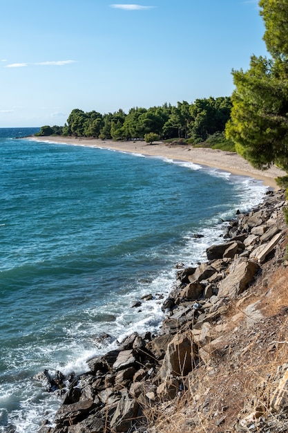 Ägäische felsige Küste Griechenlands, Strand mit wachsenden Bäumen und Büschen