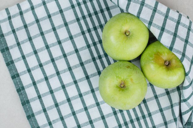 Ganze grüne Äpfel auf gestreifter Tischdecke