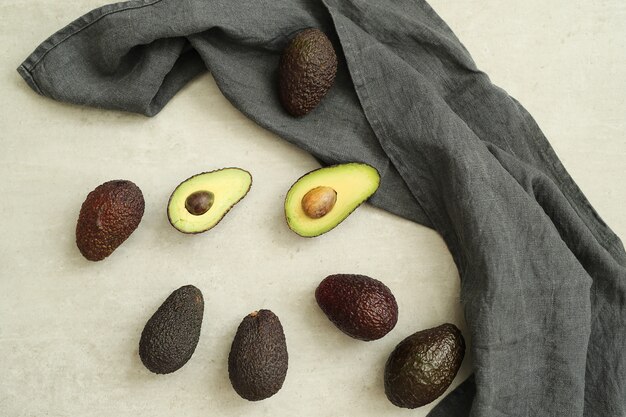 Ganze und geschnittene Avocados auf grauem Stoff