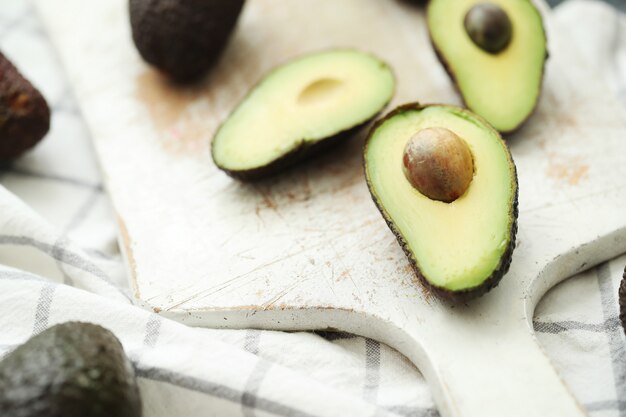 Ganze und geschnittene Avocados auf Holzschneidebrett