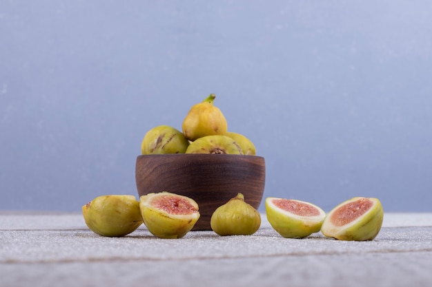 Ganze und geschnittene Feigen in einer Holzschale und in der Mitte auf dem weißen Tisch